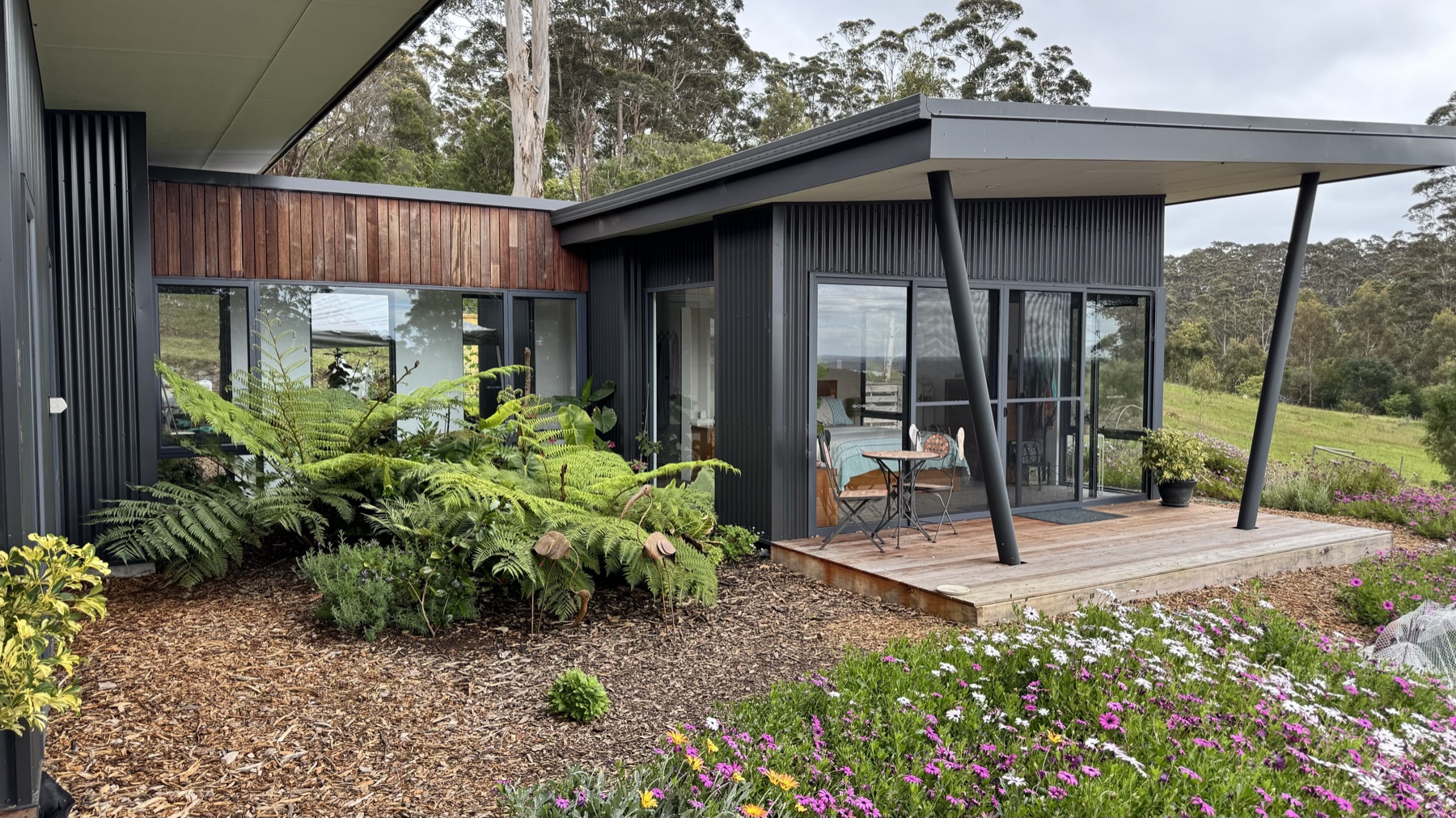 Dark-clad Denmark residence with broad roof planes among mature trees