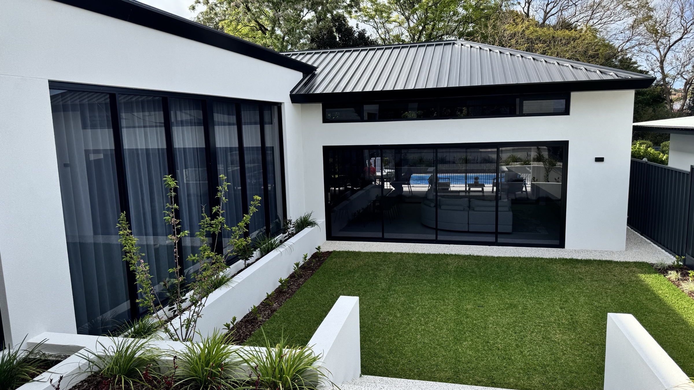 Central lawn courtyard enclosed by black-framed glazing
