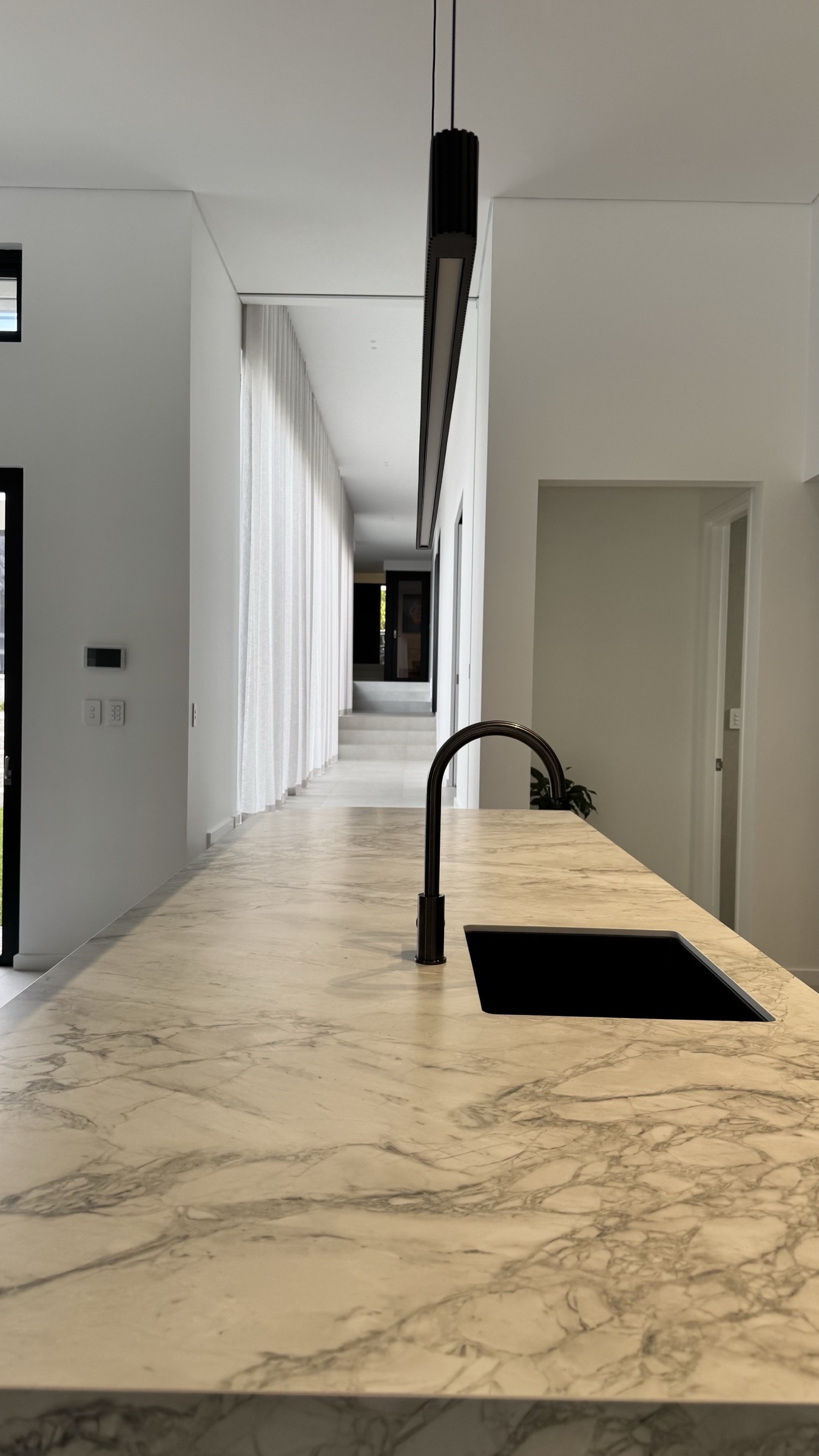 Stone kitchen island looking toward a light-filled hallway