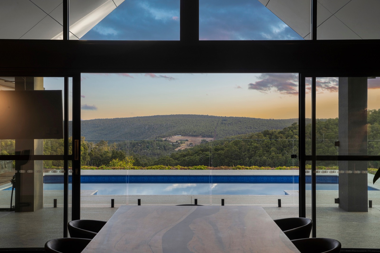 Karagullen new build looking across the pool to a forested hillside at sunset