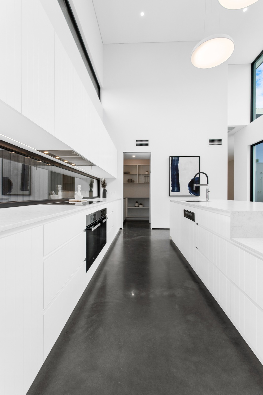 White kitchen beneath a double-height light-filled void