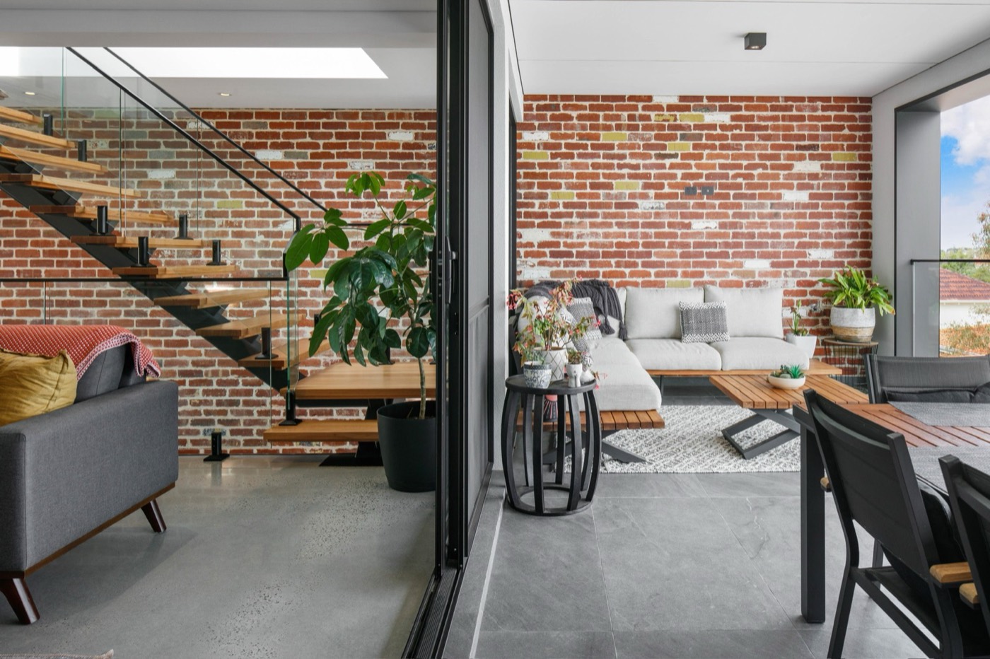 Open living space with brick wall, timber stair and black steel details